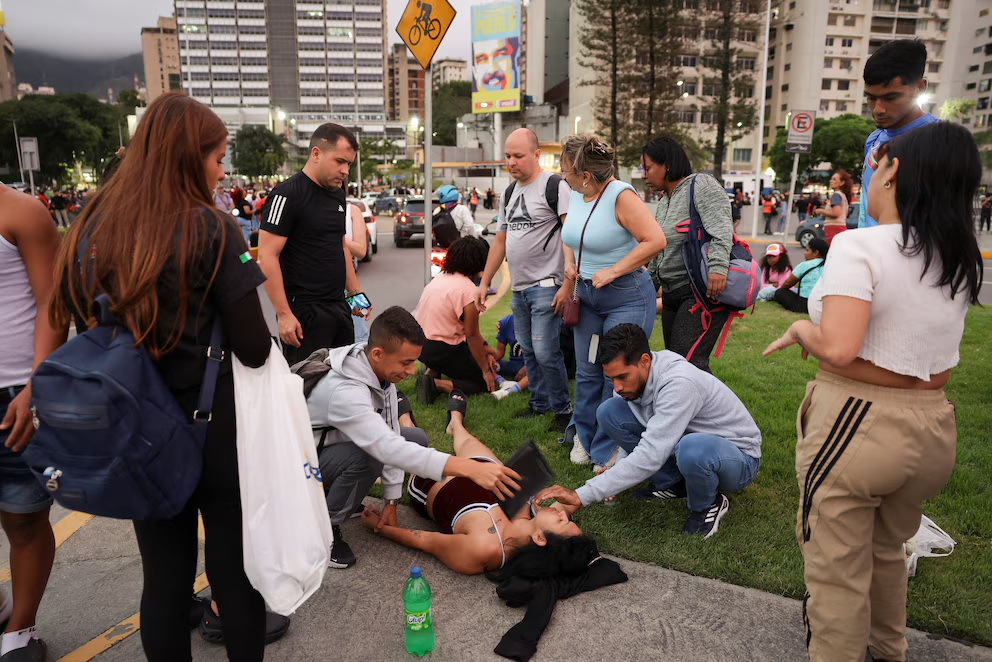 Várias pessoas ajudam uma mulher após terremoto em Caracas, Venezuela, 24 de junho de 2026 REUTERS/Gaby Ora